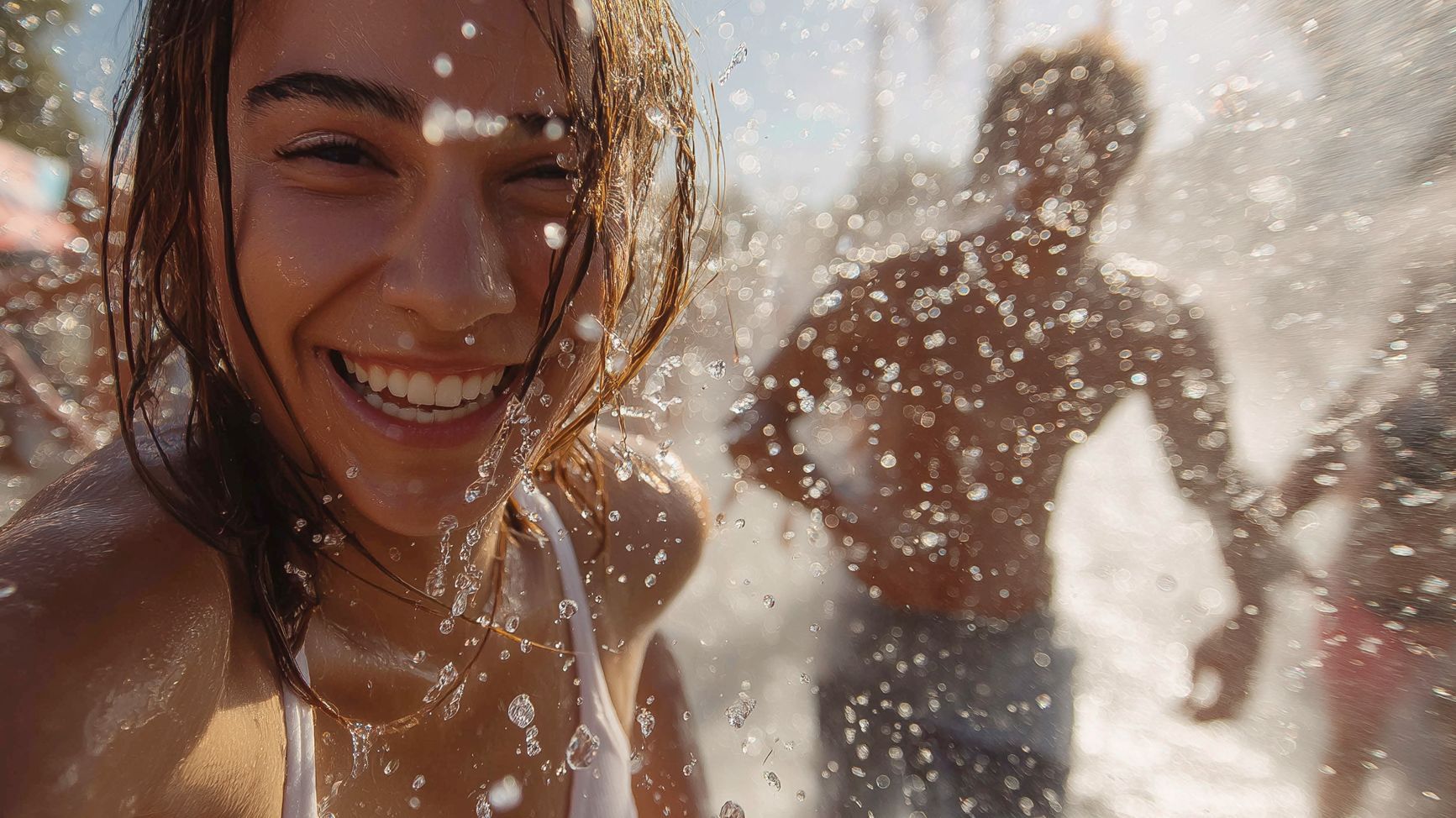 Sommeraktion Internet-Werbung – Freude und Reichweite verbinden Junge Frau lacht in die Kamera während einer Sommeraktion, Wasser spritzt – Symbolbild für erfrischende Internet-Werbung mit starker Reichweite und emotionaler Ansprache