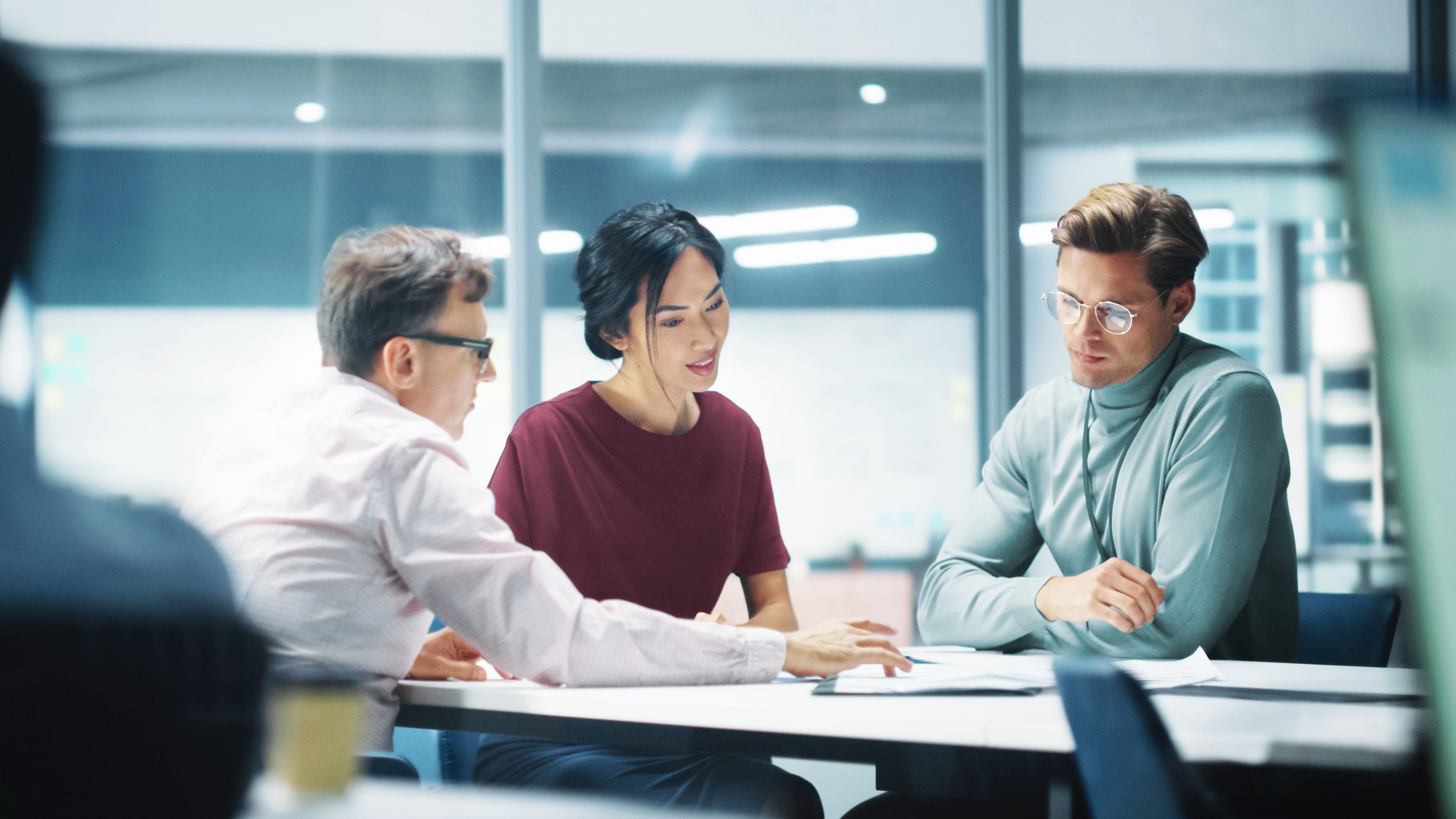 Two men and a woman at a table in a meeting