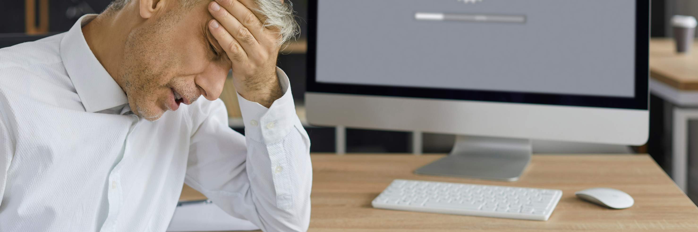 Frustration from a Slow Website – Time to Boost Performance Frustrated man in an office sitting in front of a computer with a slow-loading screen – symbolic of poor website performance