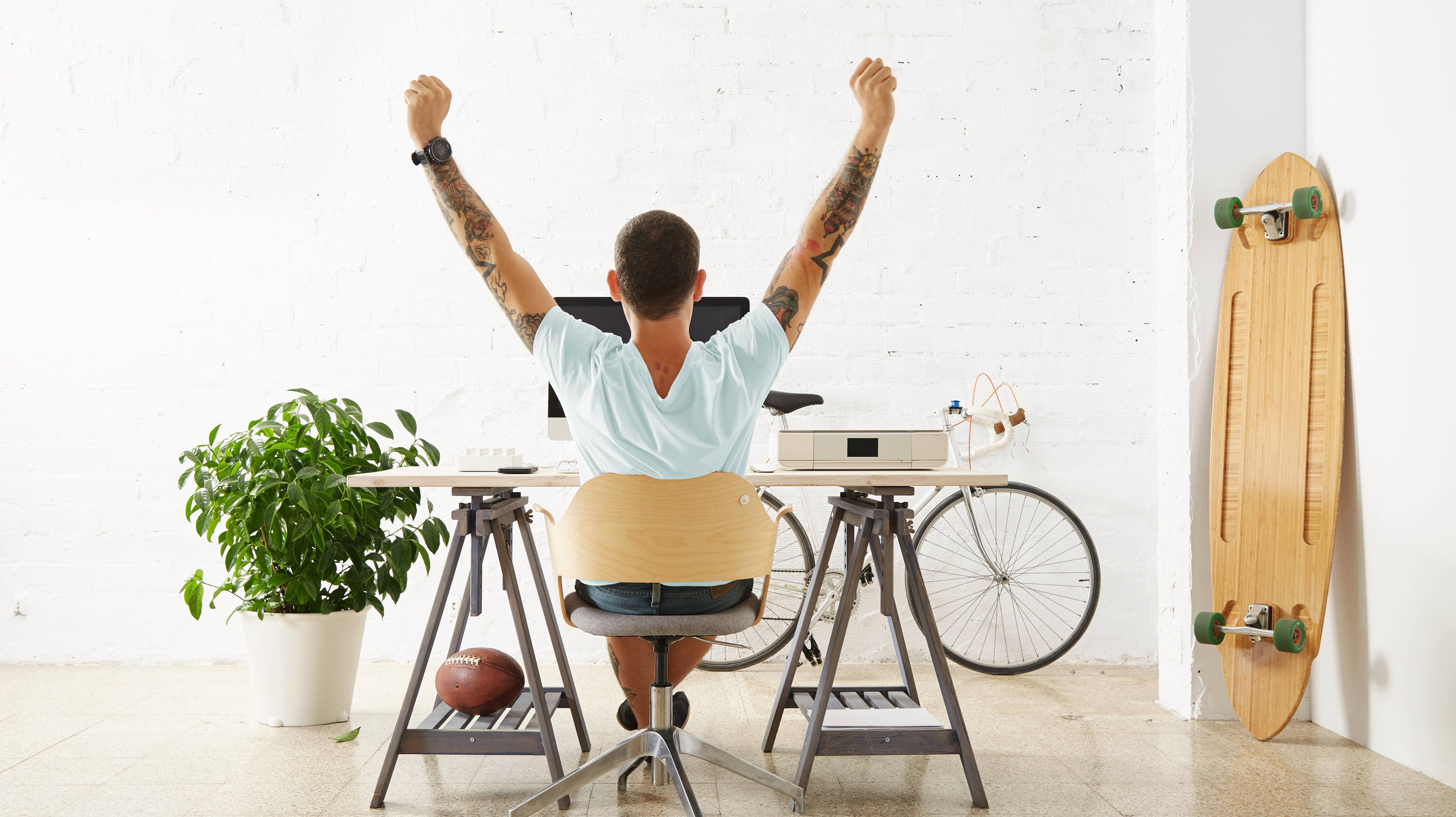 Young tatooed man is happy in his office at home